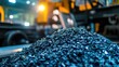 © 69 - Cobalt and nickel raw materials piled in preparation for battery manufacturing, industrial machinery slightly blurred in the background.