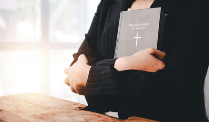 Cropped view of young woman praying with bible on table Confession concept Pray and talk with God