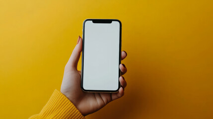 A person holding a smartphone with a blank screen against a vibrant yellow background in a bright setting