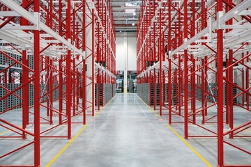 Red white racking system with grey plastic palettes inside industrial warehouse