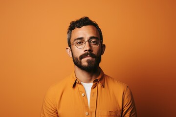 Wall Mural - portrait of handsome bearded man in eyeglasses on orange background