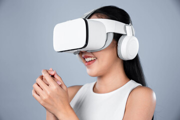 Smart female standing with gray background wearing VR headset connecting metaverse, futuristic cyberspace community technology. Elegant woman excited seeing generated virtual scenery. Hallucination.