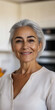 © Chari - Cheerful older woman with gray hair smiling in a bright kitchen during the daytime