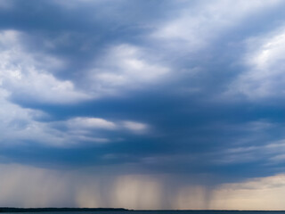 A storm and rain gray cloud floats across the sky with a visible rain band. The movement of clouds over the earth. Nature environment dark sky big clouds. Storm sky with dark pouring. clouds in sky