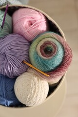 Poster - Box with colorful yarns and crochet hooks on blurred background, top view