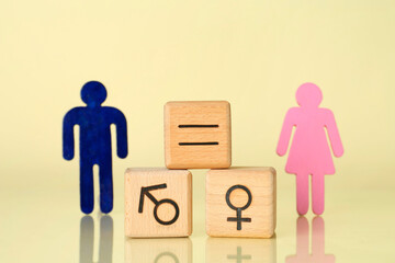 Wall Mural - Gender equality concept. Wooden cubes with male and female figures on light yellow background