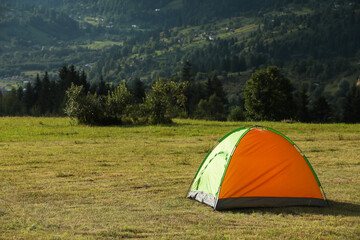 Sticker - Tent on green grass in mountains, space for text