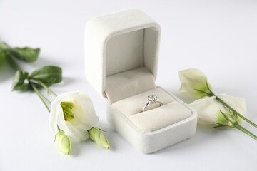 Wall Mural - Beautiful ring with gemstone in box and flowers on white background, closeup