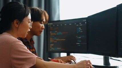 Slow motion back end software developer engineer for computer programming working together on debugging writing computing code, solving complex algorithms display on monitor in office. Burgeoning