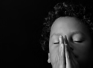 little boy praying to God with hands together on black background with people stock photo stock image