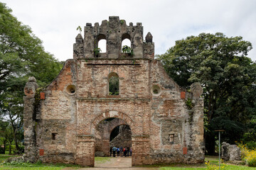 Image of the remains of a colonial-era church in Ujarras, Cartago, Costa Rica. The structure is surrounded by greenery and flowers, with a clear path leading to the entrance