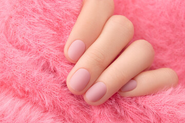 Wall Mural - Womans hand with trendy pink matte manicure close-up. Beauty treatment spa body care