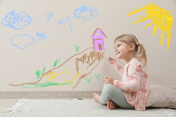 little child sitting on floor and drawing on white wall