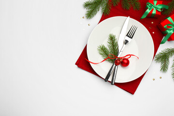 Poster - Christmas table setting with plate, cutlery, napkin and festive decor on white background, flat lay. Space for text