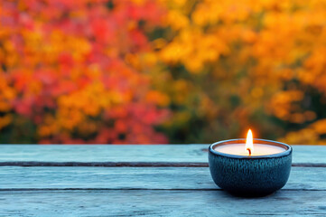 Poster - Burning candle resting on empty table with autumn background