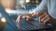 © FAQIR - API: a businessman using a laptop with a hologram of API, virtual interface that hologram of API,API integration, API development, JSON, API documentation, Application prgramming interface