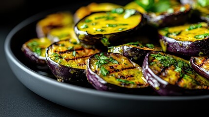 Close-up of charred eggplant slices topped with herbs on a sleek black dish, showcasing a blend of color, flavor, and presentation artistry.