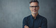 © J. Grayscale - Confident Middle-Aged Man in Glasses Smiling Against a Neutral Background