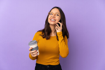 Young mixed race woman isolated on purple background holding coffee to take away and a mobile