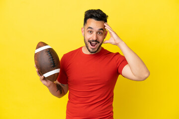 Young Caucasian man playing rugby isolated on yellow background with surprise expression