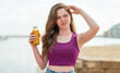 © luismolinero - Young redhead girl holding an orange juice at outdoors having doubts and with confuse face expression