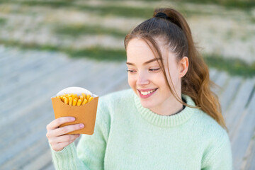 Sticker - Young pretty girl holding fried chips at outdoors with happy expression