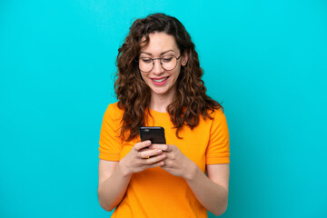 Wall Mural - Young caucasian woman isolated on blue background sending a message or email with the mobile