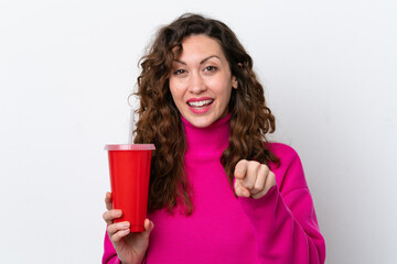 Young caucasian woman drinking soda isolated on white background points finger at you with a confident expression