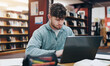 © LuxeShutter24/peopleimages.com - Learning, laptop and research with man in library for knowledge, education and college thesis. Academy, future and university with student and online portal for exam, project and scholarship