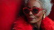 © Nataliia_Trushchenko - Woman wearing red glasses and a red coat. She is smiling. closeup portrait of an extremely hip black older woman, sunglasses, feather boa, cheeta patterned hair, on a red background