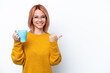 © luismolinero - Young Russian girl holding cup of coffee isolated on white background pointing to the side to present a product