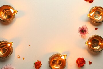 Canvas Print - Diwali celebration. Diya lamps and beautiful flowers on light textured surface, flat lay. Space for text