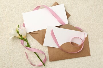 Canvas Print - Blank cards, envelopes, flower and ribbon on beige table, flat lay