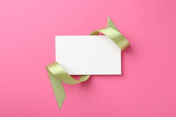 Wall Mural - Blank card and olive ribbon on pink background, top view