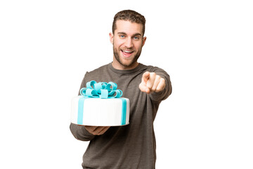 Poster - Young handsome blonde man holding birthday cake over isolated chroma key background surprised and pointing front