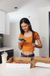 © SHOTPRIME STUDIO - Woman checking her phone in front of a pizza box in a casual setting