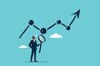 © Alya Hasna Fatimah - a businessman stands with a magnifying glass observing the rising graph growth