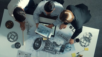 Top down view of skilled engineer working together while looking at jet engine. Aerial view of smart designer or diverse technicians brainstorming while looking at electronic generator. Alimentation.