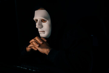 White criminal anonymous mask as hack programmer trying to approach main database server drive system on main computer in competitor company to ransom in virus privacy system at night time. Surmise.