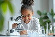© Athichai - A girl in a white dress is playing with a microscope in elementary school science class.