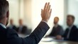 © BoOm - A businessman raising his hand to ask a question in a corporate meeting setting.