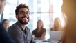© BoOm - Happy man with glasses smiling in a group meeting with bright, modern interior.