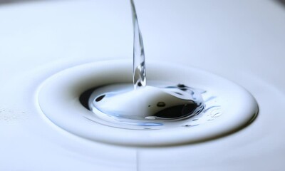 Wall Mural - a single drop of dark liquid falls into a pool of white liquid creating a ripple effect.