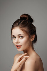 Poster - Beautiful young woman with hands on face posing on gray background