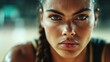 © familymedia - A close-up portrait of a focused and determined female athlete with glistening sweat on her face, showcasing intensity and concentration in a competitive environment.