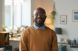 © Mediaphotos - Front view portrait of adult African American man wearing glasses and smiling a camera standing in warm home setting copy space