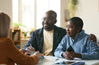 © Mediaphotos - Portrait of smiling African American couple enjoying consultation with insurance agent sitting at desk in office and signing forms copy space