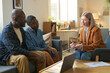 © Mediaphotos - Portrait of social services worker consulting adult African American couple at home and pointing at clipboard explaining contract forms