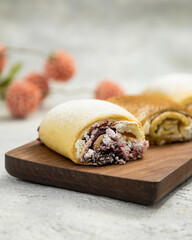 Sweet rolls with berry jam and powdered sugar lying on wooden cutting board