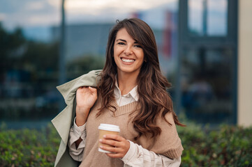 Businesswoman smiling holding coffee outside office building